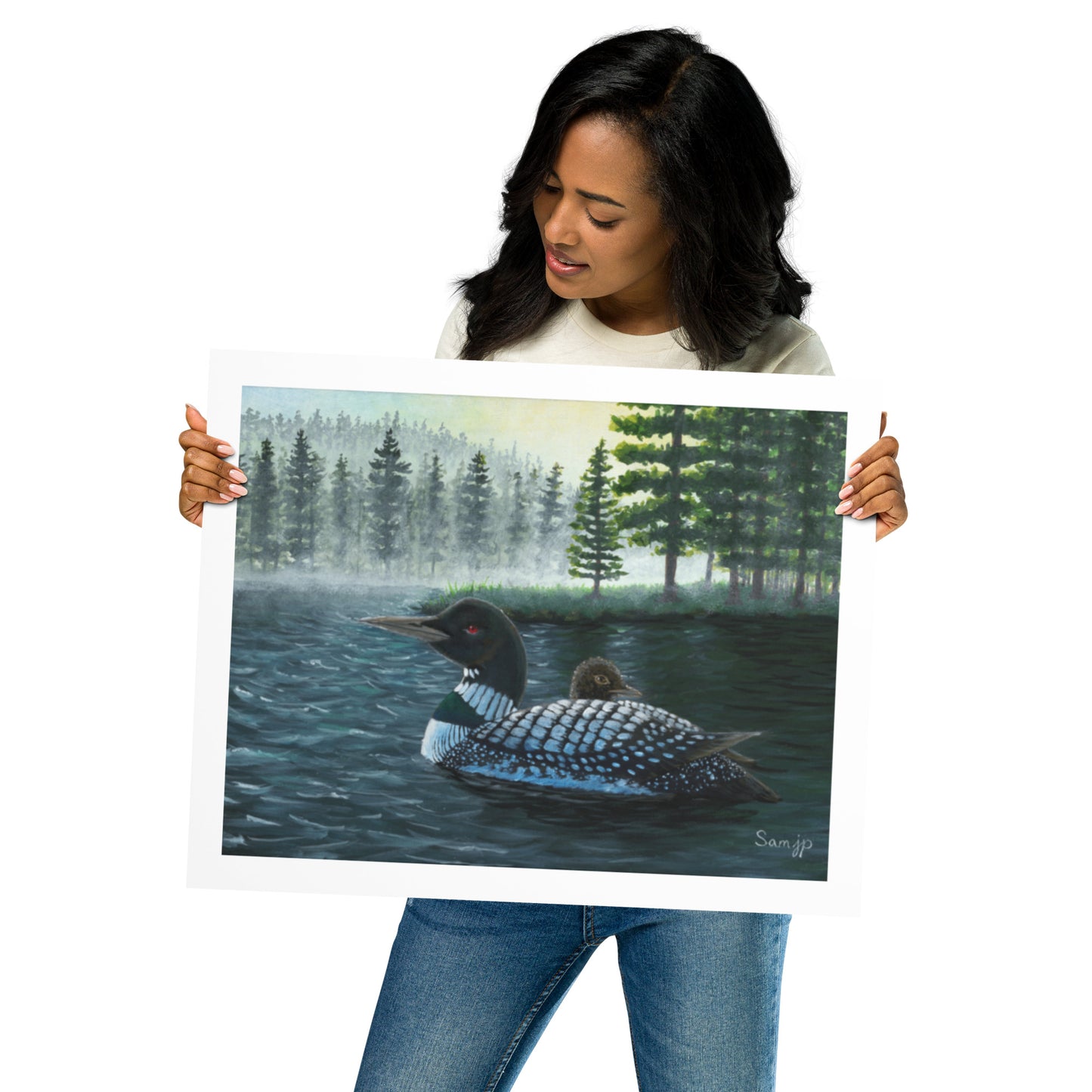 Woman holding an art print of an acrylic painting featuring a loon and chick on water, with a woodsy background.